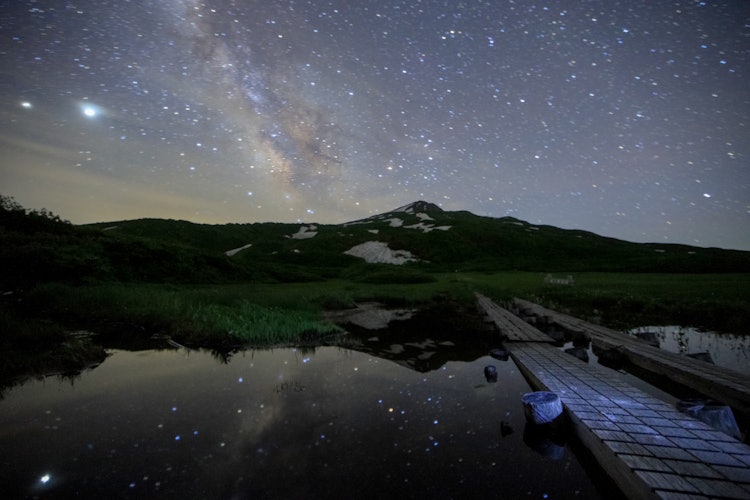 [画像1]秋田県鳥海山、祓川登山口にて撮影しました。 水鏡に鳥海山の山体と満点の星々と天の川が反射して映っています。
