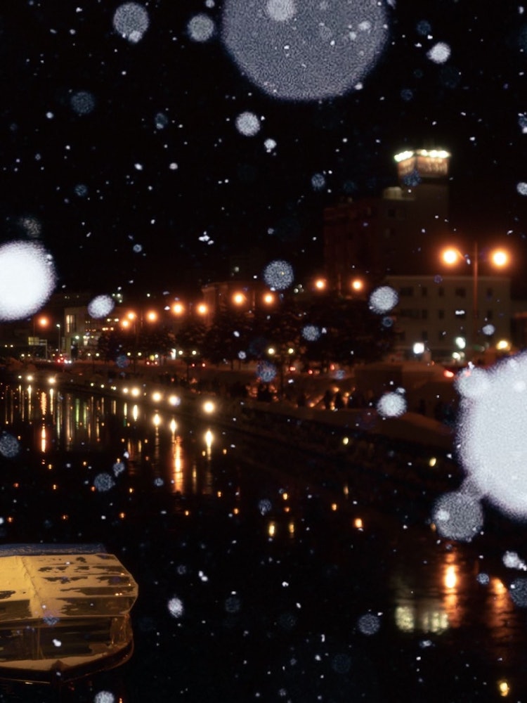 [画像1]雪降る夜と小樽運河小樽 雪あかりの路運河に浮かぶキャンドルと街明かり、多くのスノーキャンドルと道行く人寒くても何処か暖かい景色