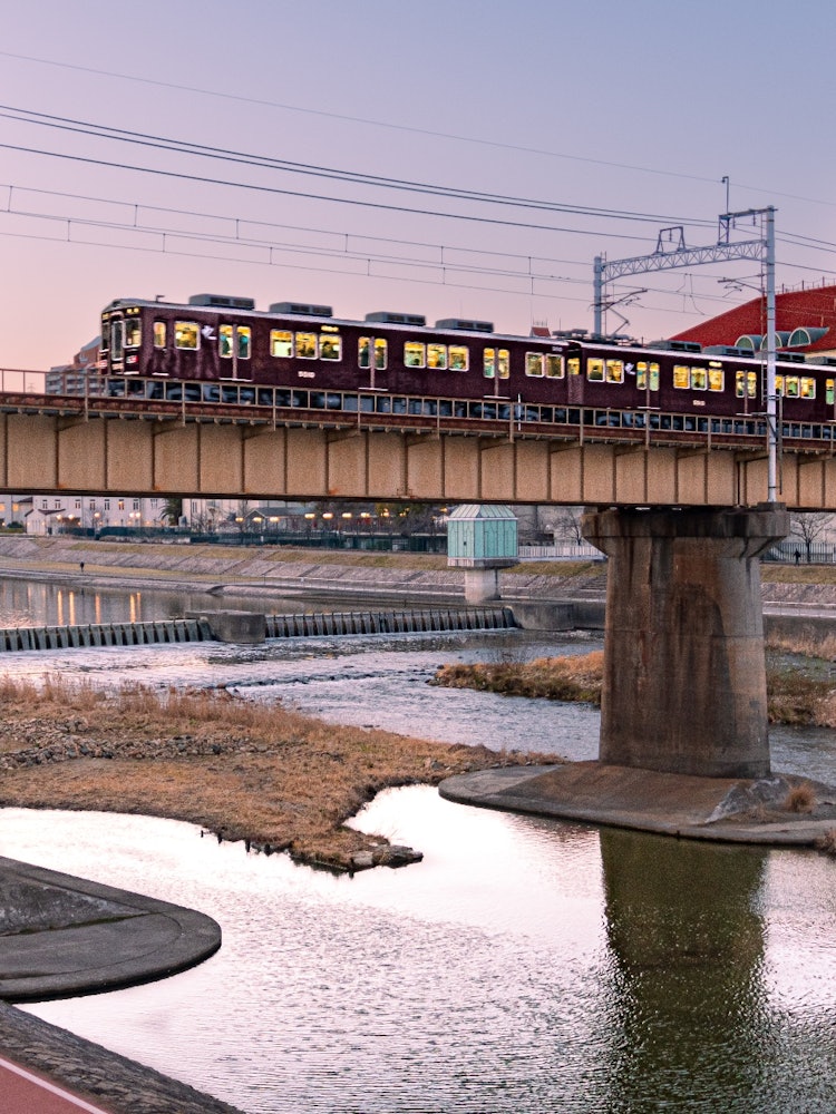 [相片1]这是宝冢。 栗色的阪急列车缓缓驶过宝冢大剧院和前面的铁桥，向川被染成夕阳的颜色。 这是美丽的宝冢镇的秘密风景。
