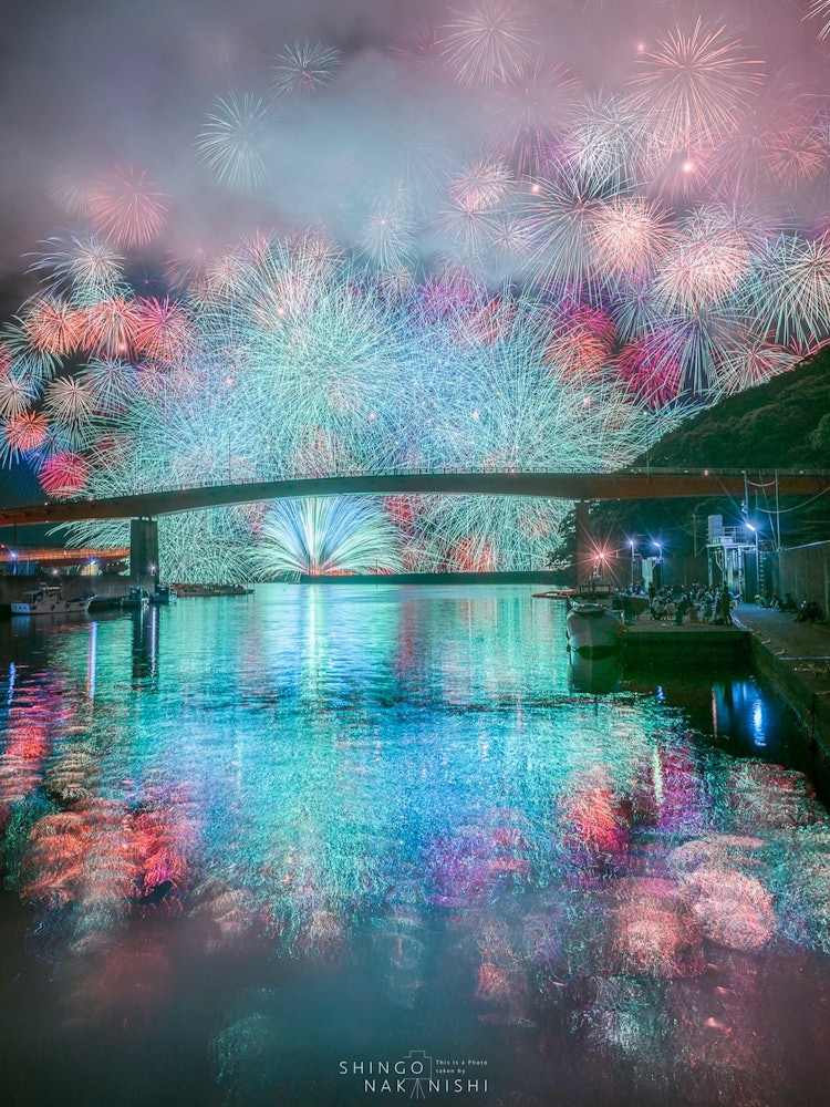 [画像1]三重県紀北燈籠祭の花火。ここの目玉の彩色千輪という花火ですが、カラフルな花が空も川も染め上げます。