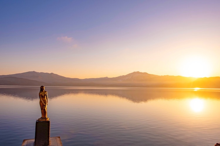 [画像1]田沢湖　辰子姫像と朝陽朝は神秘的な湖と田沢湖姫像を眺めることが出来ます。日中のコバルトブルーに映える空と湖面も美しく最高です