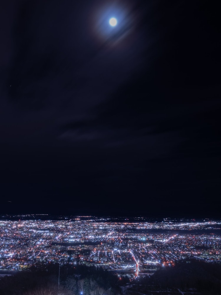 [画像1]月明りと街灯り藻岩山山頂展望台から臨む夜景です地上では夜景が光り輝き、空では満月が明るく照らしていました