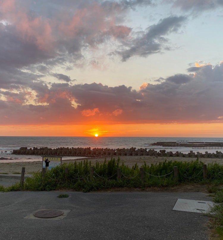 [画像1]石川県の海沿いにあるサービスエリアで撮った写真です。 夕焼けの太陽と日本海のコントラストがキレイだなと思ったので応募させて頂きます！