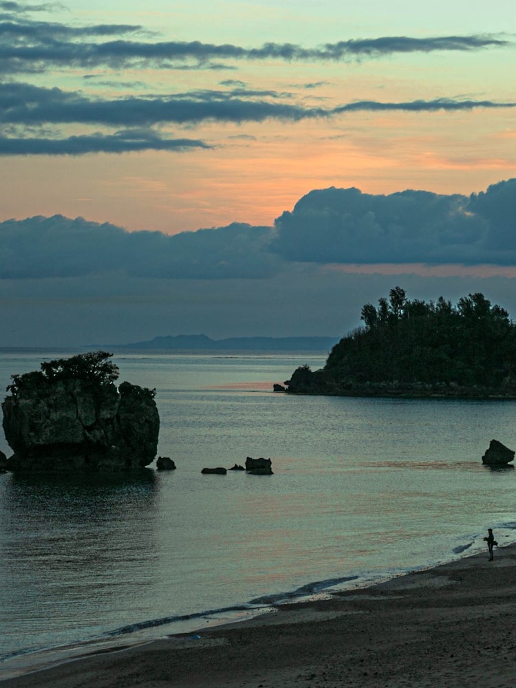 [画像1]沖縄目覚めの朝。海岸で迎える朝のひと時。静寂の中たたずむ人影。