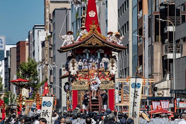 [画像1]酷暑の京都祇園祭長刀鉾に稚児さんが乗り込むところを撮影。稚児さんはお祓いを受けてから地面に足を付けることができないため大人が肩に乗せて鉾まで乗り込む習わしがあるようです。