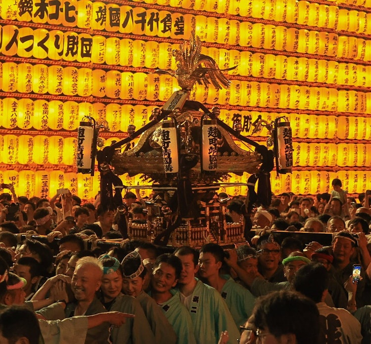 [相片1]這是在東京都千代田區靖國神社舉行的三玉祭上拍攝的照片之一。 手持者和神輿被通道一側的無數燈籠照亮，進一步增強了神性。