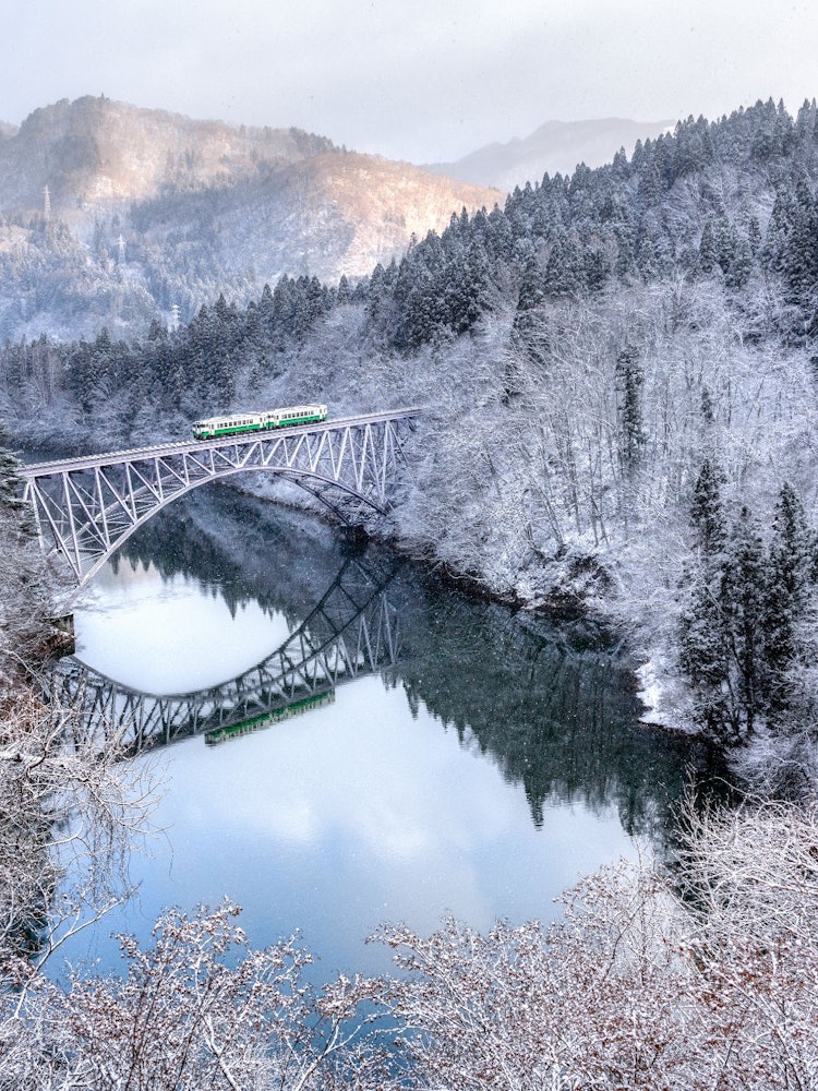 [相片1]只见线和白雪皑皑的景观。第一座桥和火车倒映在只见川上，营造出非常梦幻的风景。