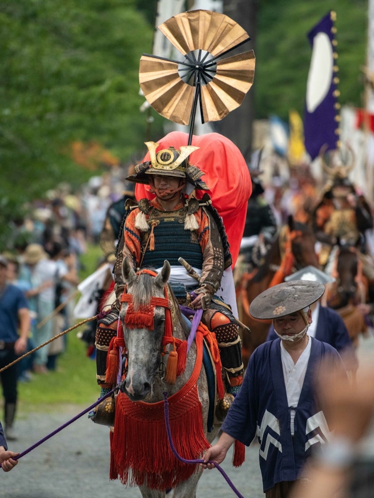 [画像1]福島県相馬地方で行われる「相馬野馬追祭」総大将が乗馬し、中村神社の参道を通り城の外に出る。