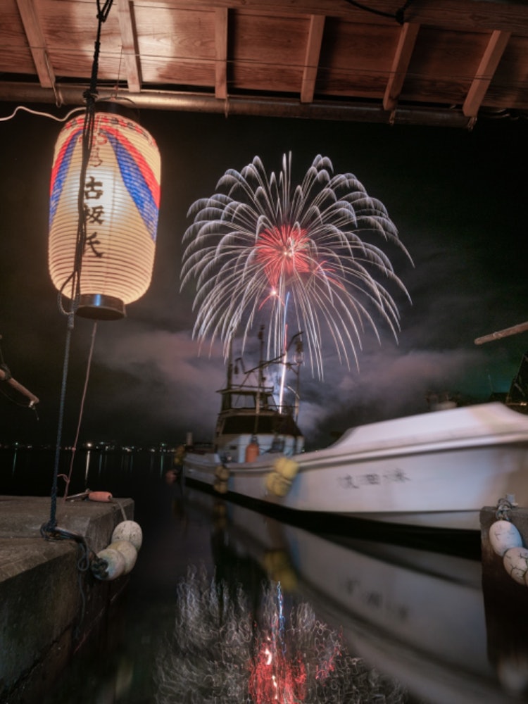 [画像1]京都府与謝郡伊根町、この町には一階が船着場となった舟屋という伝統的な漁師の建物が数多く残ります。年一回行われる伊根花火をその舟屋の格納庫から見ました。御神灯の明かり、格納庫に反響する花火の音、全てが古