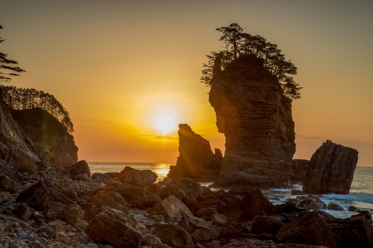 [相片1]它是位於岩手縣宮古市三陸海岸的山王岩石。 日出的美麗光芒神聖地將海岸的岩石染成了金色。
