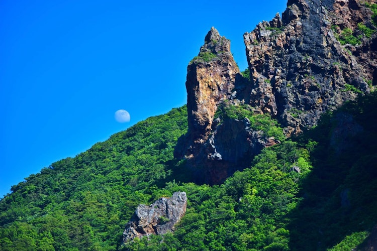 [相片1]在綠色山丘後面的晴天，可以看到滿月。當我在小樽的藍洞游輪之旅中，我看到了這美麗的風景。深藍色的天空，綠色的丘陵地區和魔法月亮創造了令人驚歎的景色。地點：北海道小樽