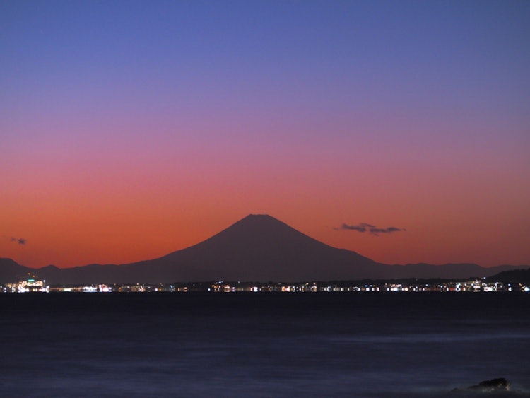 [画像1]千葉県金谷港から、東京湾と富士山対岸の街灯が海の広さを感じます。夕闇の中でも富士山の存在感は雄大です。