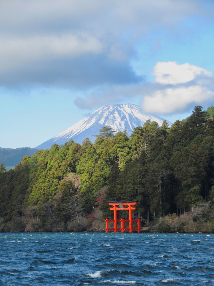 [画像1]パワースポットとして有名な箱根神社は、芦ノ湖のほとりにその鳥居を構えている。 少し風が強かったこの日は、曇り空から青空とともに富士山が雄大な姿を現し、とても荘厳な雰囲気の風景になりました。