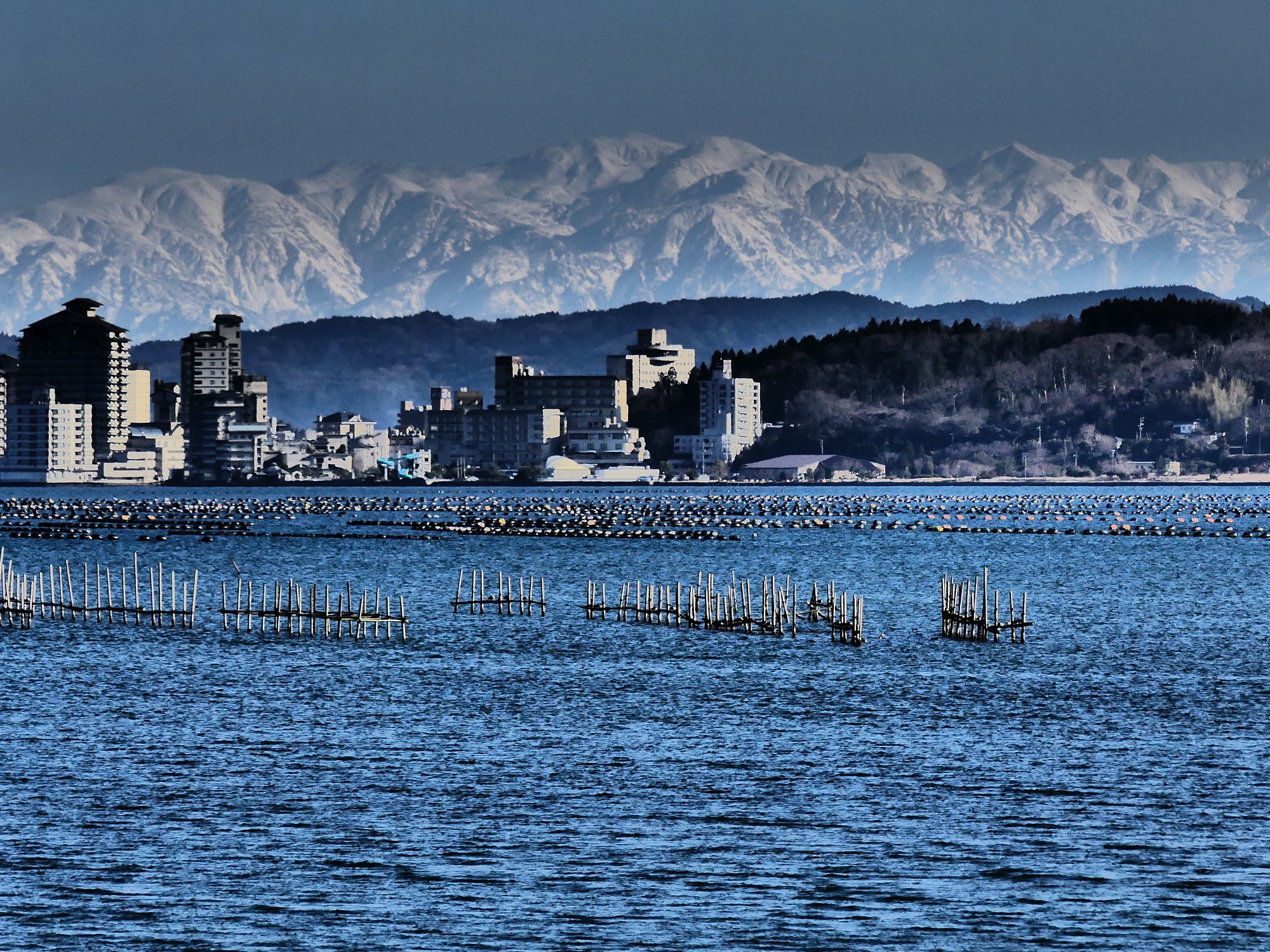 rokuzan六山さんの投稿｜「七尾湾岸からの白馬連山」能登島大橋や和倉温泉街を対岸にし、立山連峰を眺められる位置にもある。  特に白馬や五竜、唐松など後ろ立山連峰が大きく迫って見えるのがいい。七尾湾岸の中島地区にて｜【石川県】【七尾西湾】【立山連峰】【フォト ...