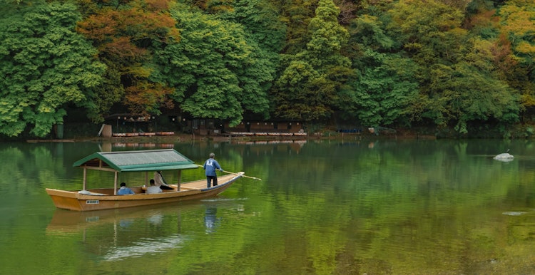 [相片1]依偎在京都嵐山川岸邊，一幅幕降臨，訴說著日本永恆的美麗和豐富的遺產。在這裡，過去與現在交匯，樹葉在微風中搖曳，輕輕地落在水面上，就像精緻的記憶一樣。這條河是過去幾個世紀的無聲見證，反映了樹葉的鮮豔色調